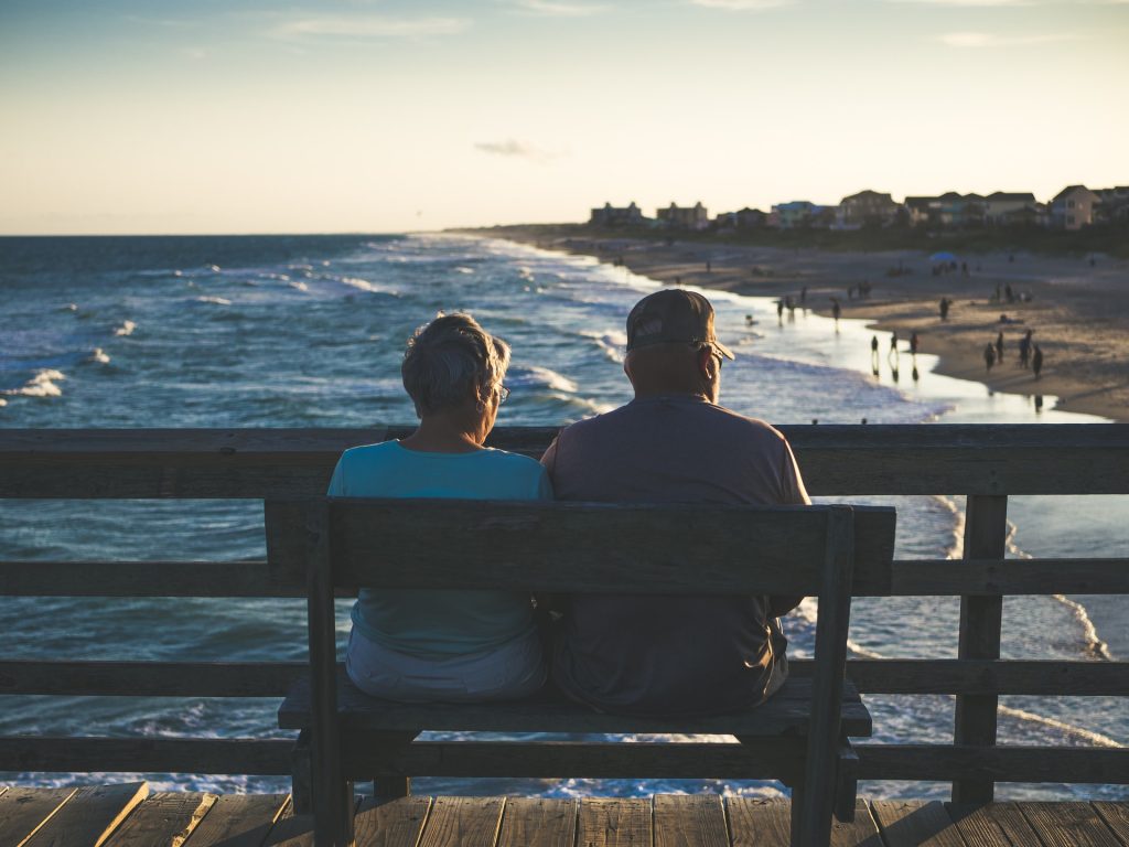 Two retired seniors sitting on a bench in Florida.